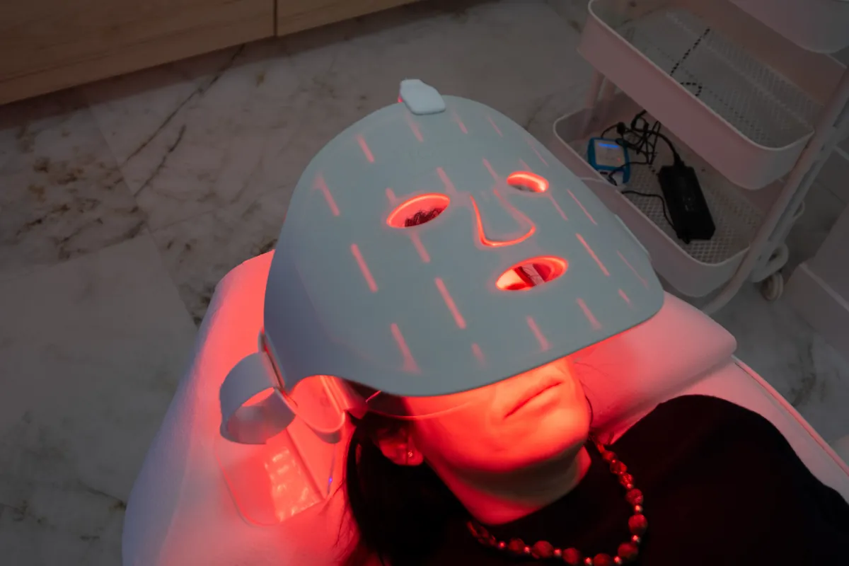 Paciente con máscara de luz roja durante una sesión facial en Clínica GM